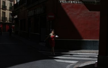 A woman holds a coffee set as she crosses a zebra crossing in the Andalusian capital of Seville