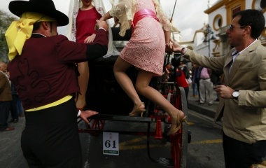 A woman is helped by men to gets on a carriage before participating in a carriages exhibition in The Maestranza bullring of the Andalusian capital of Seville, southern Spain