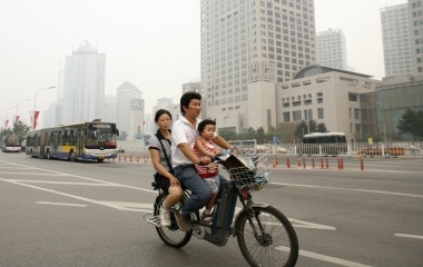 People ride a moped in Beijing ahead of the Beijing 2008 Olympic Games