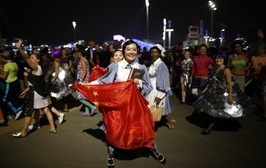 A performer holding a China flag laugh after participating in the opening ceremony next to the Olympic Stadium at the Olympic Park in London