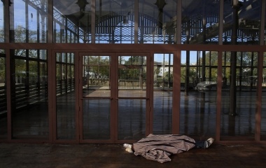 A man sleeps next to the entrance of an empty exhibition hall in the Andalusian capital of Seville