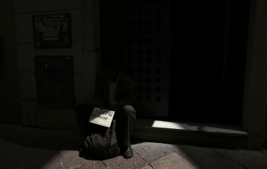 A man sits on a doorway as he asks for alms in the Andalusian capital of Seville, southern Spain
