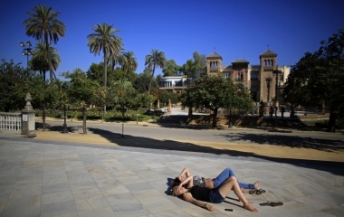 Young tourists lies on the floor outside the archaeological museum in the Andalusian capital of Seville