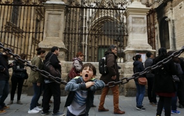 Tourists queue to enter the cathedral as a boy yawns in the Andalusian capital of Seville, southern Spain
