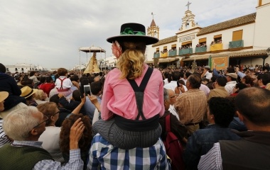 Pilgrim sits over shoulders of a man as they see the Virgin of El Rocio during a procession around the shrine of El Rocio in Almonte, southern Spain
