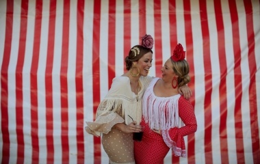 Women wearing typical Sevillana outfits laugh during the traditional Feria de Abril (April fair) in the Andalusian capital of Seville