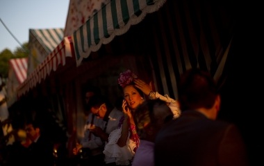 A woman wearing a Sevillana dress uses a cell phone during the traditional Feria de Abril (April fair) in the Andalusian capital of Seville