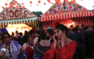 A woman wearing a Sevillana dress uses a mobile phone during the traditional Feria de Abril (April fair) in the Andalusian capital of Seville