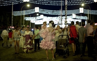 A woman wearing a Sevillana dress holds a baby as she poses for a photo during the traditional Feria de Abril (April fair) in the Andalusian capital of Seville