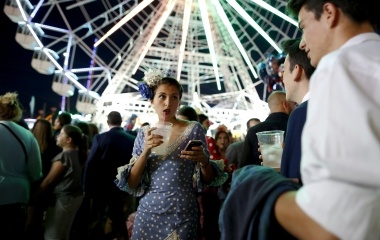A woman wearing a sevillana dress drinks during the traditional Feria de Abril (April fair) in the Andalusian capital of Seville