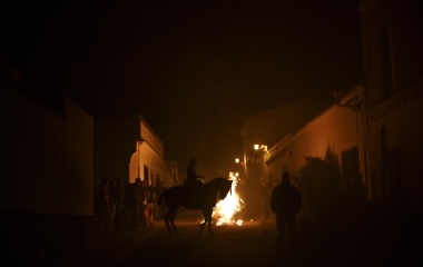 A young woman rides a horse next to a bonfire during the "Luminarias" annual religious celebration on the night before Saint Anthony's, patron of animals, in the village of Alosno, southwest Spain
