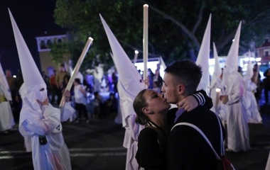 A couple embrace next to San Gonzalo procession during Holy Week in the Andalusian capital of Seville