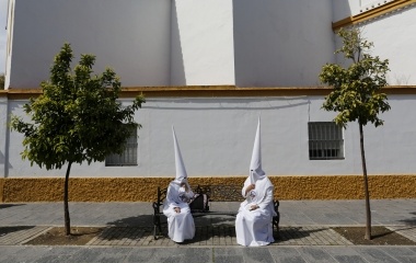 Penitents of San Gonzalo brotherhood sit as they wait to take part in a Holy Week procession in the Andalusian capital of Seville, southern Spain