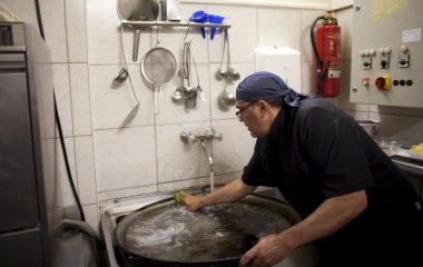 Jose Manuel Abel, 46, washes a paella pan during his second working day as a kitchen assistant in Munich
