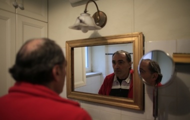 Jose Manuel Abel, 47, looks at himself in the mirror before leaving at home in Munich