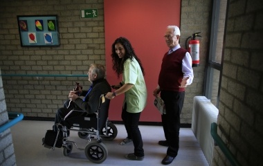 Spanish nurse Maria Jose Marin pushes an elderly man on a wheelchair in the nursing home in the Hague
