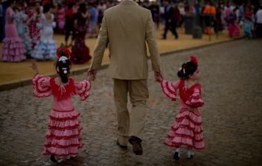 Girls wearing a Sevillana dress walk with a man during the traditional Feria de Abril (April fair) in the Andalusian capital of Seville