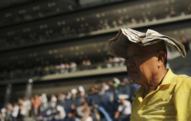 A spectator uses a newspaper to cover himself from the sun in the Hong Kong Jockey Club in Hong Kong