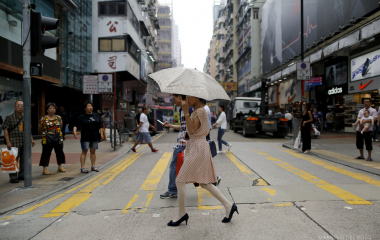 A woman with an umbrella crosses a zebra crossing in Mong Kok district in Hong Kong