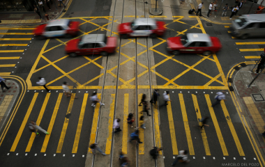 Taxis and pedestrians cross Des Voeux road Central in the Central district in Hong Kong