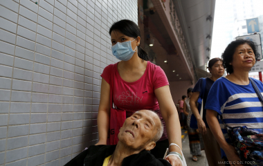 A woman pushes a man sitting on a wheelchair in the Mong Kok district in Hong Kong