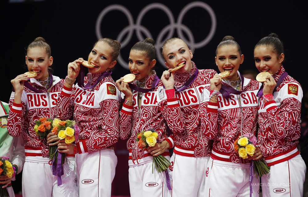 Team Russia bite their gold medals in the victory ceremony after the group all-around rhythmic gymnastics final at the London 2012 Olympic Games